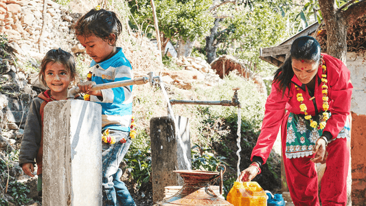 kleine Kinder und eine Mutter, welche rund um einen Brunnen stehen